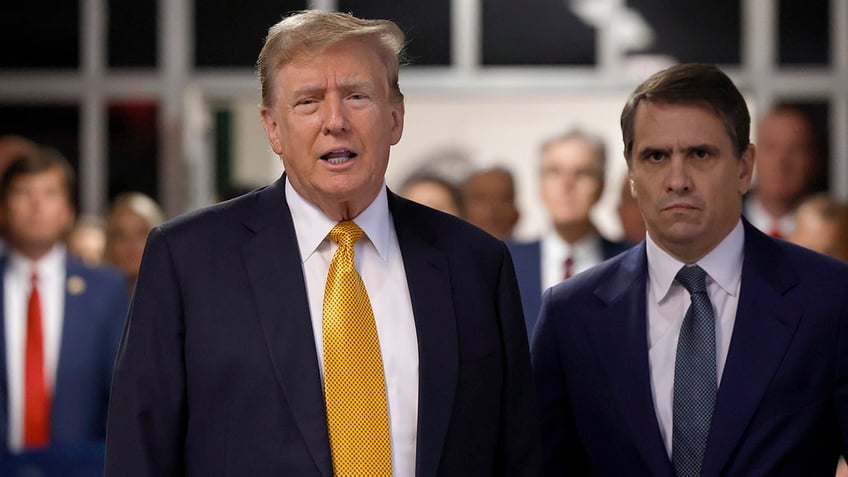 Donald Trump speaks to members of the media before entering the courtroom with his attorney Todd Blanche