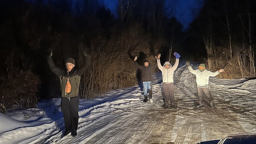 Migrants with their hands in the air in New York after crossing the Canadian border