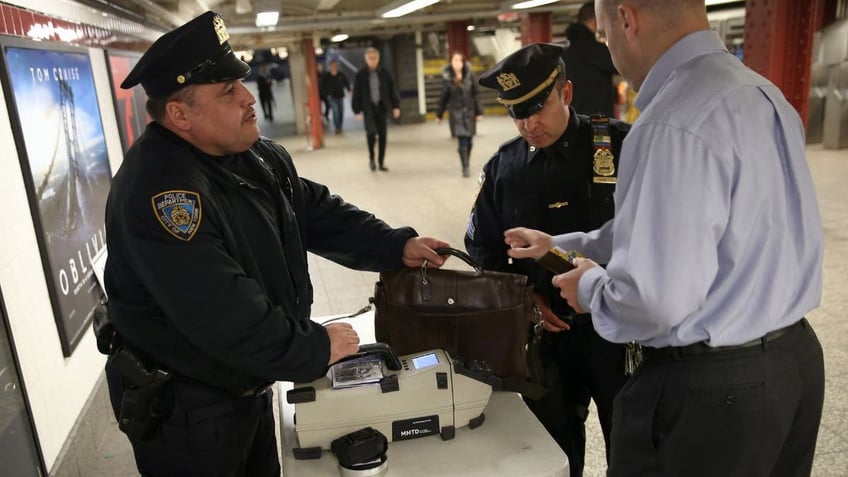 Police checking a man's bag in a subway station