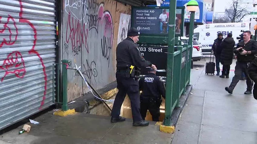 An NYPD officer is seen entering the 182-183rd St. subway station after a 45-year-old commuter was shot dead Friday morning