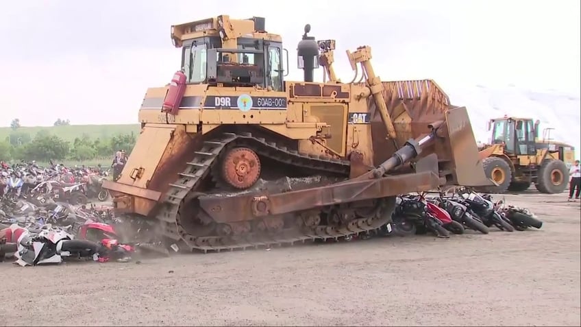 bulldozers driving over mopeds and scooters