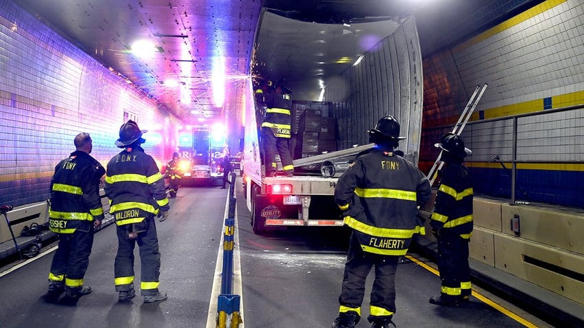 nyc firefighters seen cutting apart truck that got wedged in tunnel causing traffic nightmare