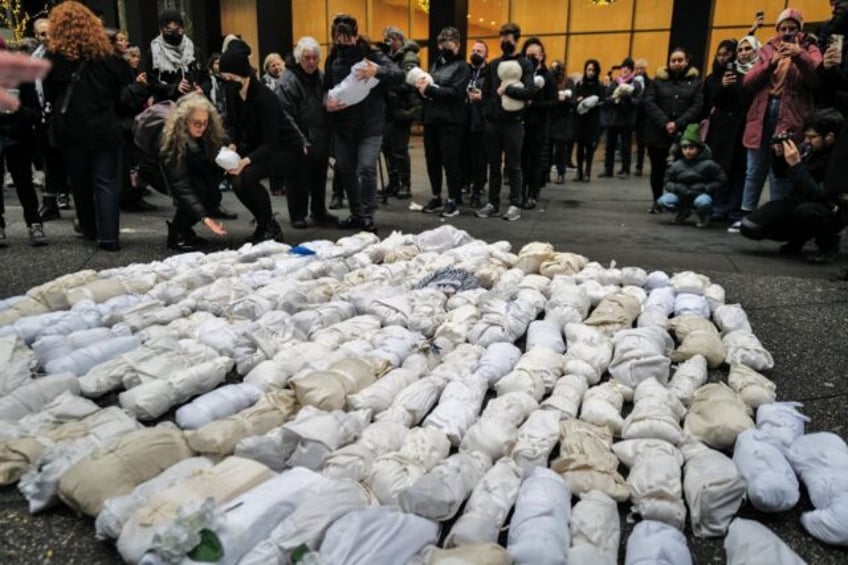 People gather and mourn in front of 500 baby dolls wrapped in a shroud, in remembrance of children killed in the Gaza Strip, in New York on December 28, 2023.