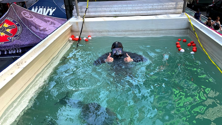 navy diver gives a thumbs up from a dive tank