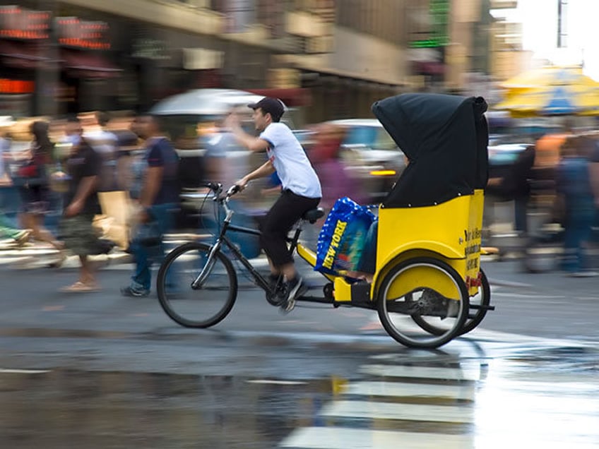 Pedicab moving quickly through pedestrians in the city - stock photo