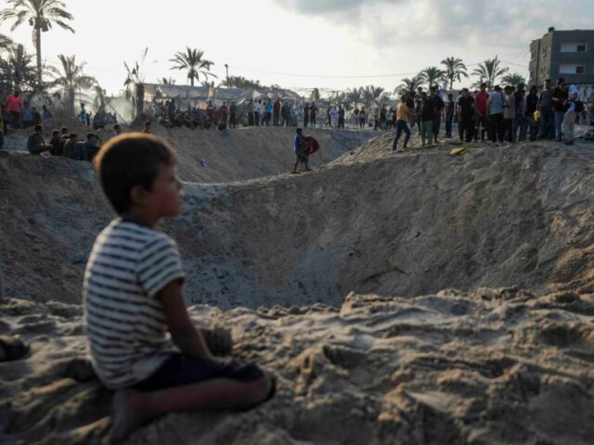 Palestinians look at the destruction after an Israeli airstrike on a crowded tent camp hou