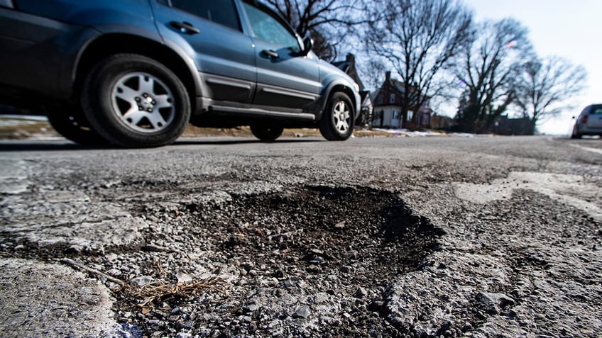 car drives past pothole