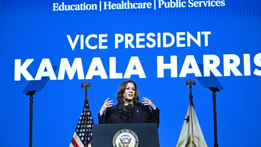 Kamala Harris speaking underneath large blue sign