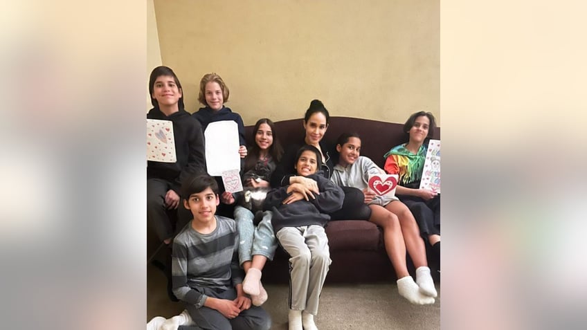 Nadya Suleman sits on the couch with seven of her kids, several holding cards for Mother's Day