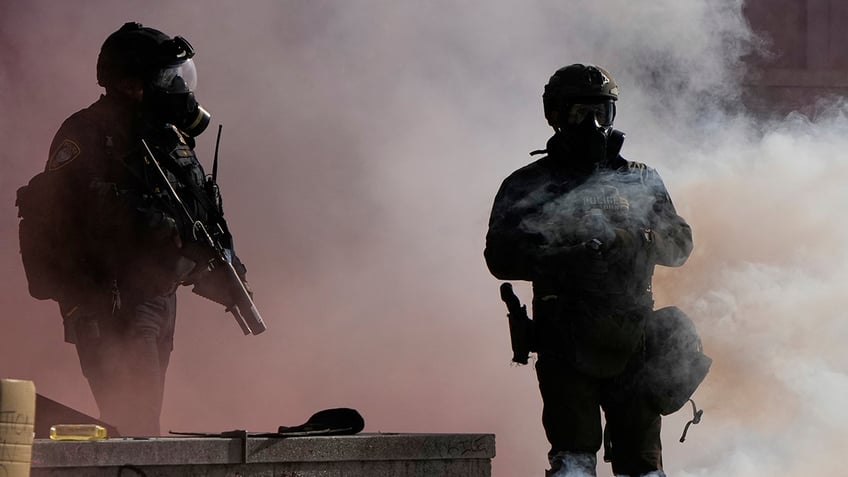 Law enforcement agents stand after tear gas was deployed outside the U.S. Immigration and Customs building during a protest Saturday, June 14, 2025, in Portland, Ore.