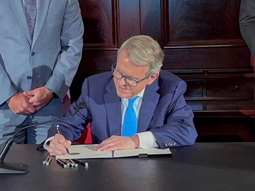 Ohio Governor Mike DeWine signs an executive order allowing college athletes in Ohio to earn money off their name, image and likeness Monday, June 28, 2021, at the Ohio Statehouse in Columbus, Ohio. The order would bring Ohio up to speed with more than a dozen states who now prevent universities or college athletic conferences from punishing athletes if they are compensated based on their sports performance. (AP Photo/Farnoush Amiri)