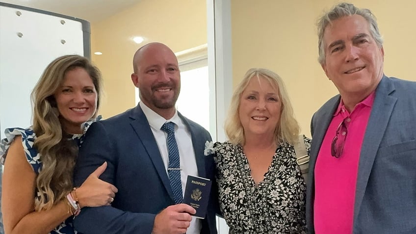 Ryan Watson, second from left, smiles with his family and holds his passport