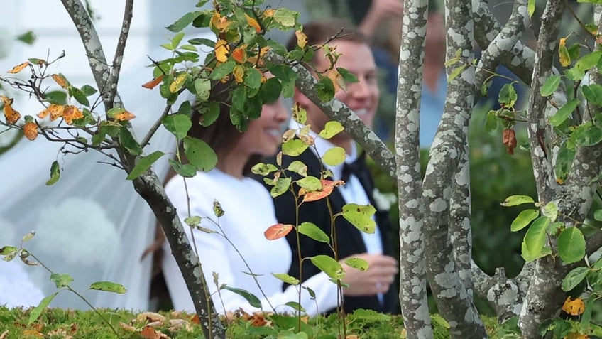 Through the trees you can see Olivia Culpo and Christian McCaffrey seated at their wedding