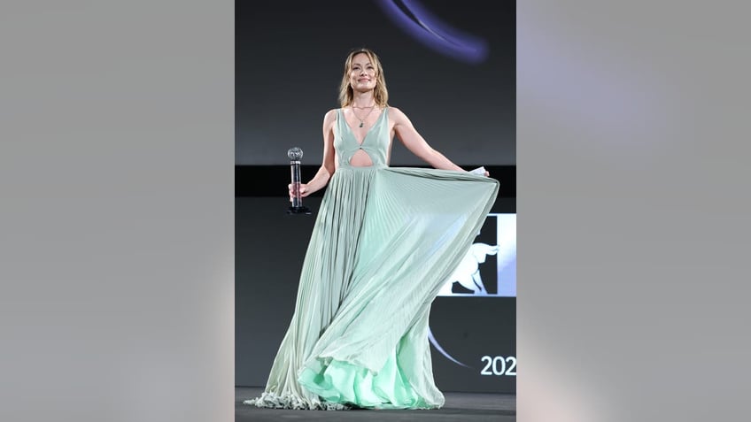 Olivia Wilde smiles and holds her award while on stage at the Taormina Film Festival. 
