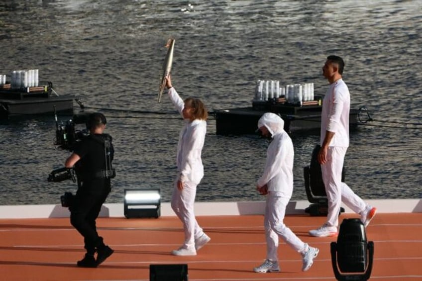 Paralympic sprinter Nantenin Keita (L) carries the Olympic flame with French rapper Jul an