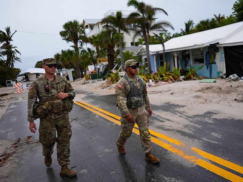 Members of the Florida Army National Guard walk past a home slated for demolition after be