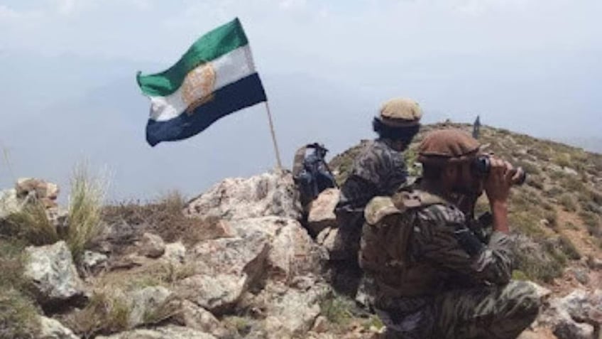 NRF fighters stand behind the flag representing the National Resistance Front of Afghanistan