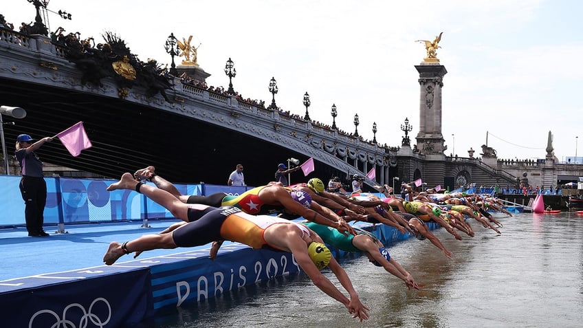 Athletes are shown diving into the Seine to start the swimming stage of the men's individual triathlon at the Paris 2024 Olympic Games in central Paris on July 31, 2024. 