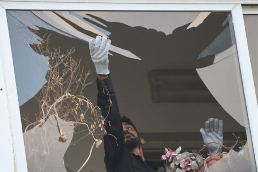 An Israeli policeman collects glass shrapnel from the window of a building damaged in the