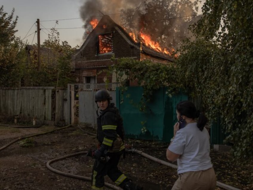 TOPSHOT - Ukrainian firefighters try to extinguish the fire in a house following an air at