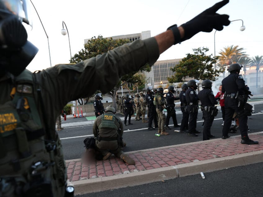 A US Border Patrol agent gestures near another arresting a protester near the United State
