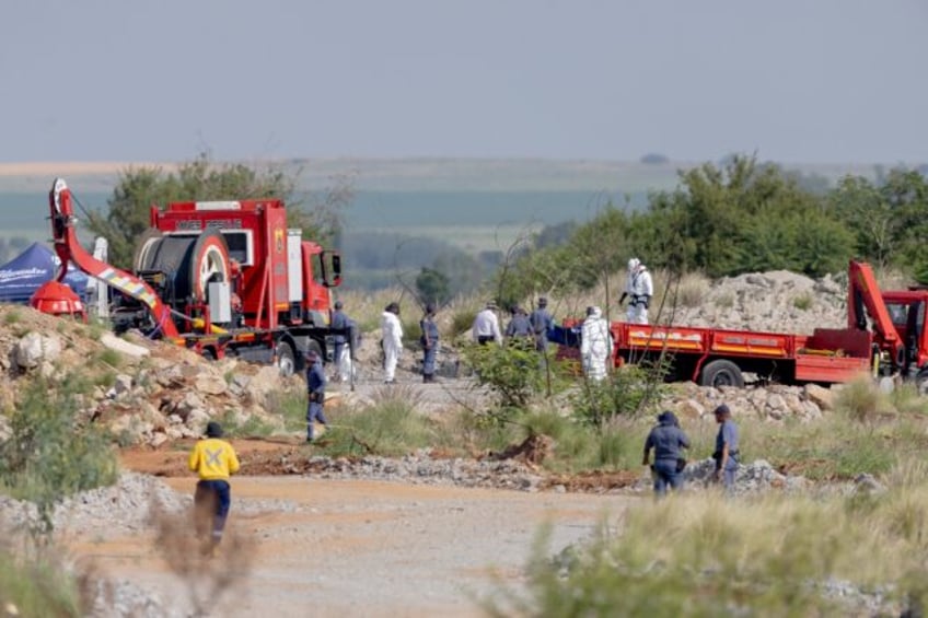 Rescuers and South African Police Service (SAPS) officers carry remains in blue body bags