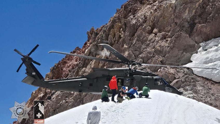 rescuers approaching National Guard helicopter on mountain