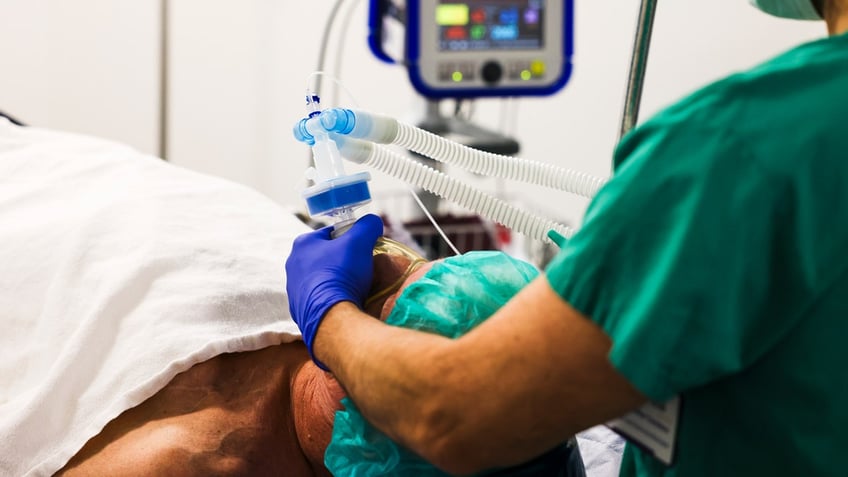 An anesthetist places a mask on a patient's face.