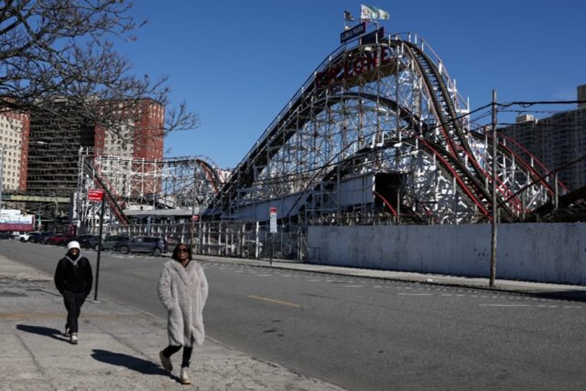 Pedestrians walk past the famous Cyclone wooden roller coaster in Coney Island, a scene al