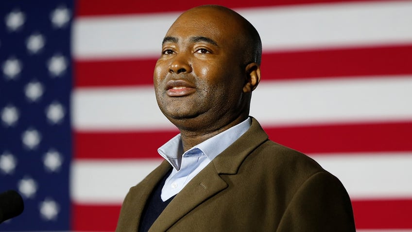 Jaime Harrison stands by a flag