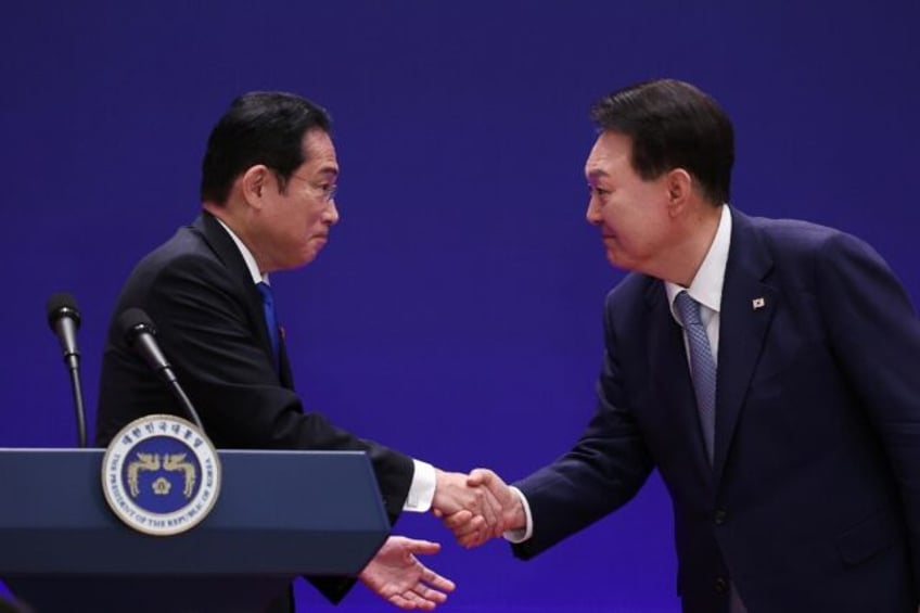 Japan's Prime Minister Fumio Kishida (left) shakes hands with South Korea's President Yoon