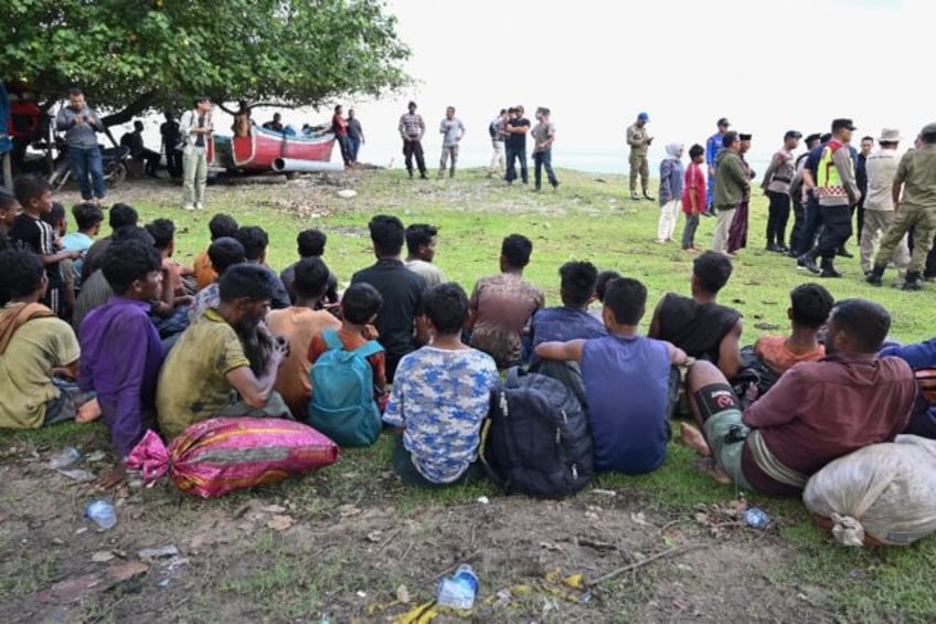 Rohingya refugees rest on a beach in Indonesia's western Aceh province after spending weeks adrift at sea