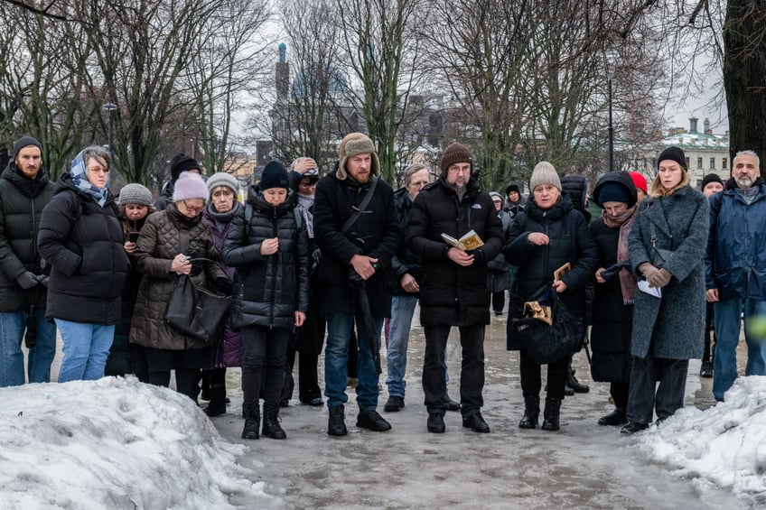 ST PETERSBURG, RUSSIA - 2024/02/17: People read a civil memorial service (a secular farewell ceremony for a deceased person) near a monument to victims of political repression to honor the memory of Russian opposition leader Alexei Navalny the day after the news of his death, in St. Petersburg. (Photo by Andrei Bok/SOPA Images/LightRocket via Getty Images)