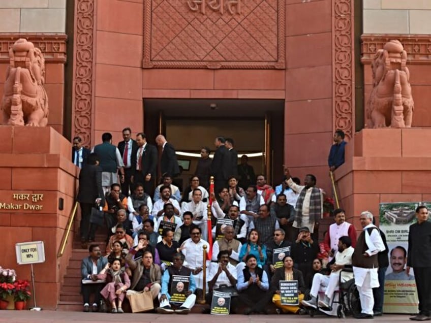 Indian lawmakers sit on the stairs of the parliament building in protest against the suspension of lawmakers, in New Delhi, India, Tuesday, Dec. 19, 2023. Dozens of opposition lawmakers were suspended on Monday after they held a protest demanding the home minister give a statement on the security breach in …