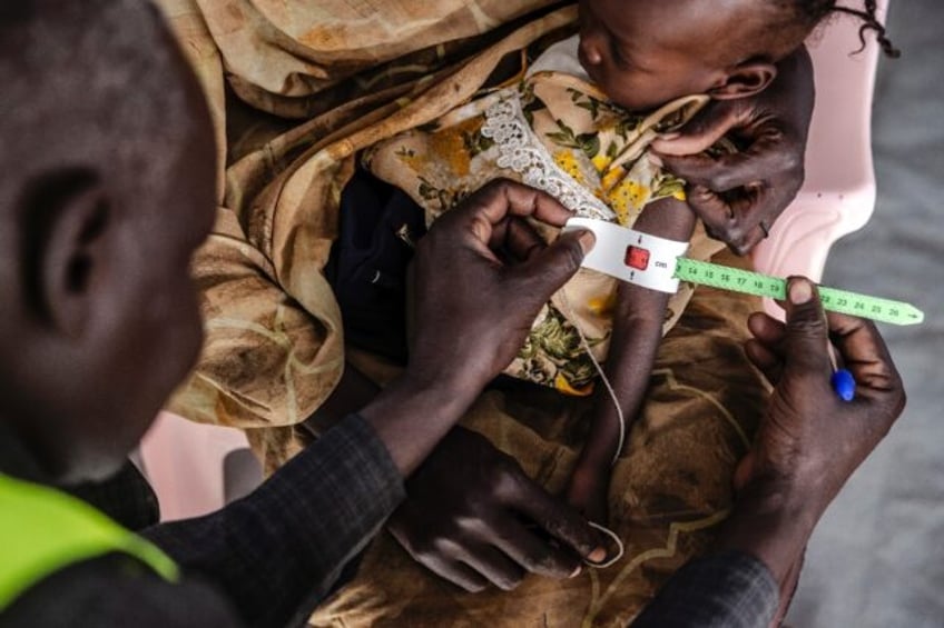 A health worker measures a Sudanese child's arm at a clinic in Renk, in neighbouring South