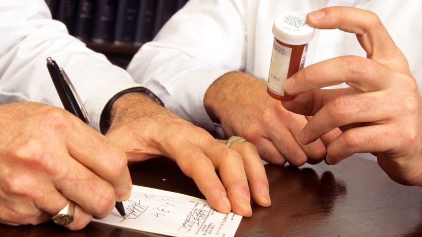A doctor pens a refill prescription