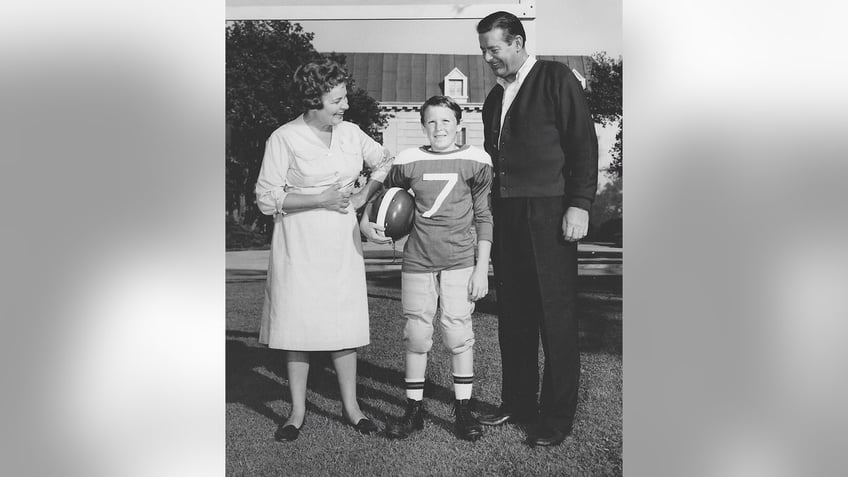 Ron DeFore wearing football gear in between his father Don DeFore and Hazel