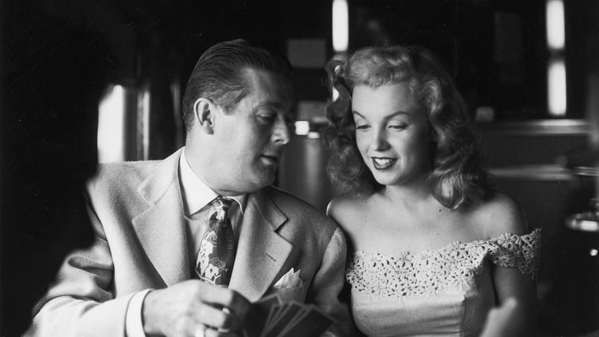 Don DeFore sitting in a train next to Marilyn Monroe