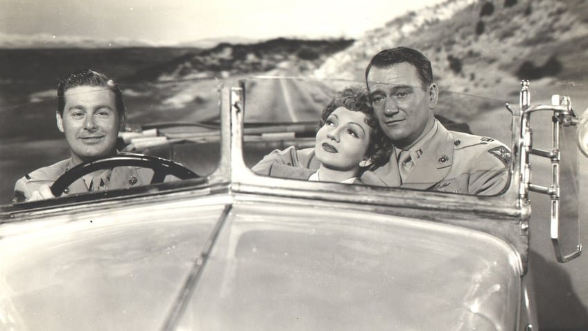 Don DeFore, Claudette Colbert and John Wayne acting out a film scene together.