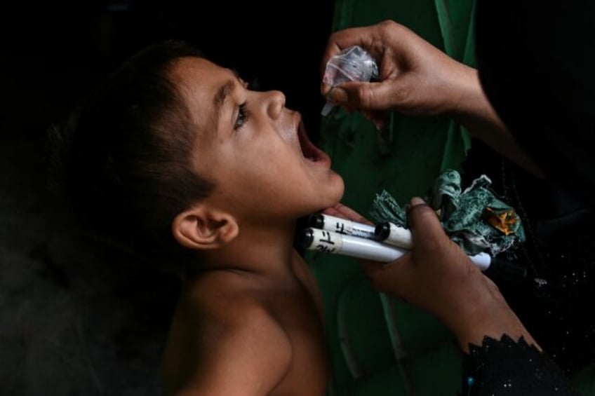 A child receives a dose of polio vaccine during a door-to-door vaccination campaign in Kar