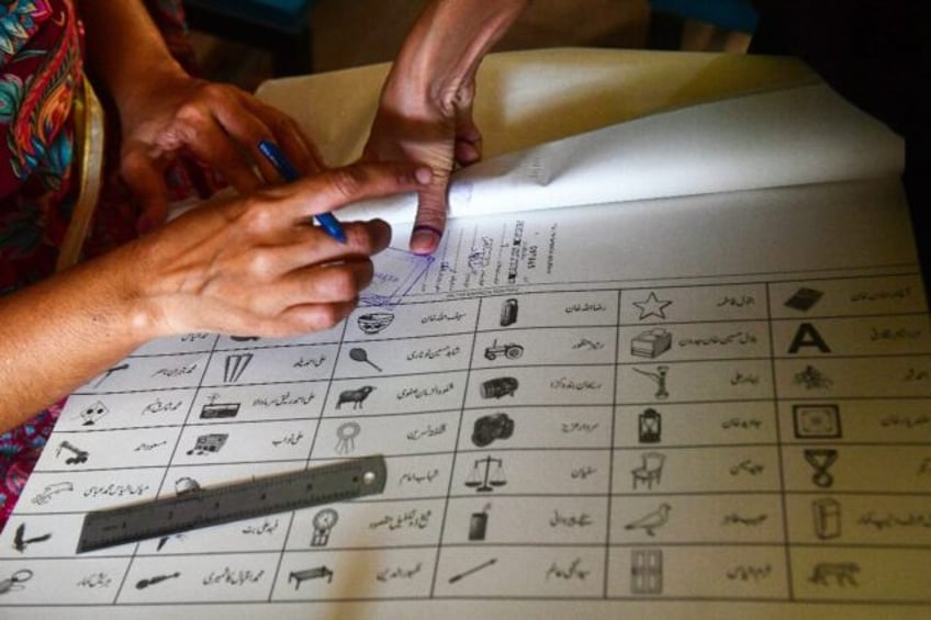 A woman marks a ballot paper with a fingerprint in Karachi during national and provincial