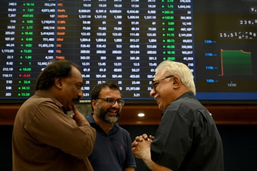 Smiling stockbrokers interact during a positive trading session at on the Pakistan stock e