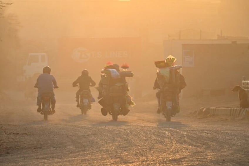 Commuters ride along a street engulfed in smog in Lahore