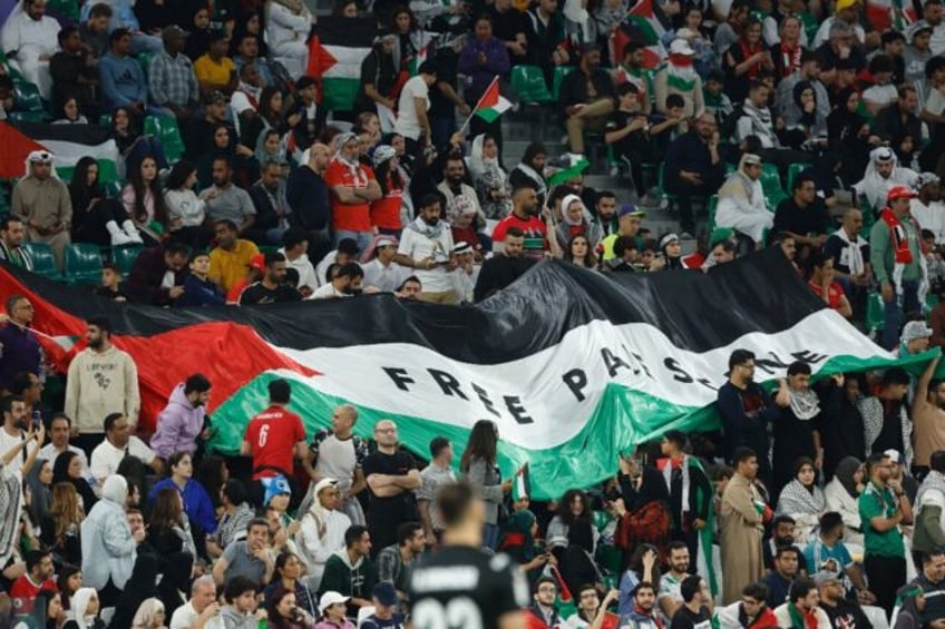 Football fans unfurl a giant Palestinian flag emblazoned with the slogan 'Free Palestine'in the stands during the Qatar 2023 AFC Asian Cup Group C football match between Iran and Palestine