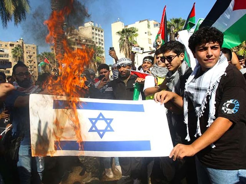 Lebanese and Palestinian students burn a copy of the Israeli flag during a solidarity rally with the Palestinians of the Gaza Strip, in Martyrs' Square in the coastal city of Sidon, in southern Lebanon on October 26, 2023, amid the ongoing battles between Israel and the Palestinian group Hamas. Thousands …