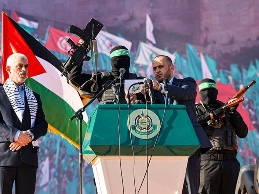 Yahia al-Sinwar (2nd-L), Gaza Strip chief of the Palestinian Islamist Hamas movement, stands by as a masked fighter of Hamas' Qassam Brigades holds up a firearm reportedly belonging to Israeli soldier Hadar Goldin (whose body is believed to be held by Hamas since the 2014 Gaza conflict), while addressing supporters …