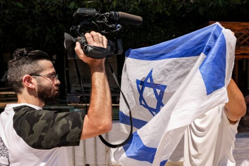 (FILES) An Israeli right-wing activist holds up an Israeli national flag to obscure the ca