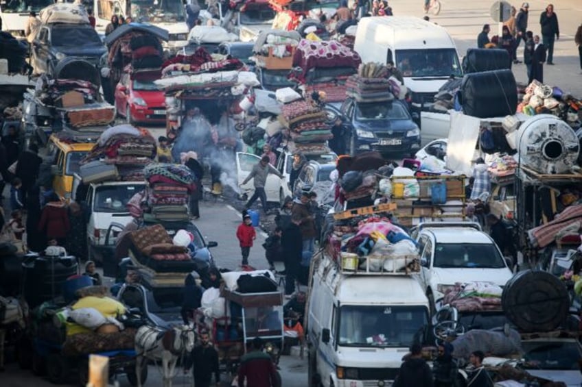 Displaced Palestinians wait along the Salah al-Din road in Nuseirat near the blocked Netza