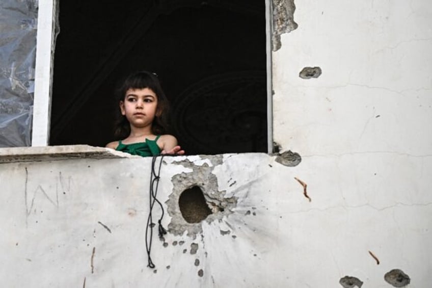 A Palestinian girl at the window of a shrapnel-pocked building in Jenin after the raid