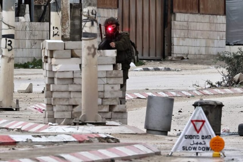 An Israeli soldier takes aim from a checkpoint in the Nur Shams refugee camp